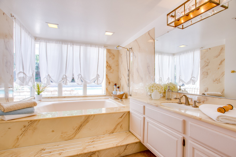 Idee per una stanza da bagno tradizionale con lavabo sottopiano, ante con bugna sagomata, ante bianche, vasca sottopiano e pareti beige