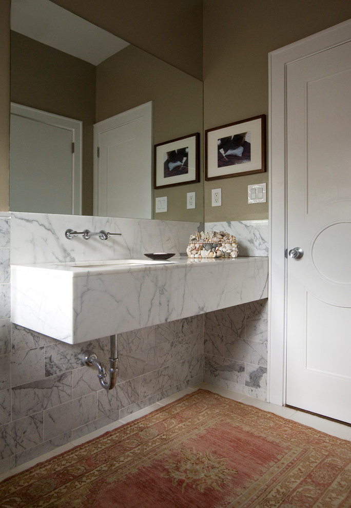 На фото: ванная комната среднего размера в стиле модернизм с врезной раковиной, мраморной столешницей, ванной в нише, душем над ванной, белой плиткой, каменной плиткой, бежевыми стенами и мраморным полом
