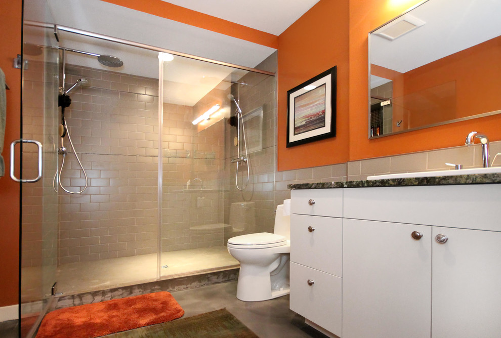 На фото: ванная комната среднего размера в современном стиле с накладной раковиной, плоскими фасадами, белыми фасадами, столешницей из гранита, открытым душем, унитазом-моноблоком, серой плиткой, керамогранитной плиткой, оранжевыми стенами, бетонным полом, коричневым полом, душем с распашными дверями и разноцветной столешницей с