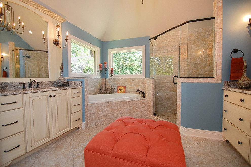 Exemple d'une douche en alcôve principale chic en bois vieilli de taille moyenne avec un placard à porte plane, une baignoire d'angle, WC séparés, un carrelage beige, un carrelage de pierre, un mur bleu, un sol en calcaire, un lavabo encastré et un plan de toilette en granite.