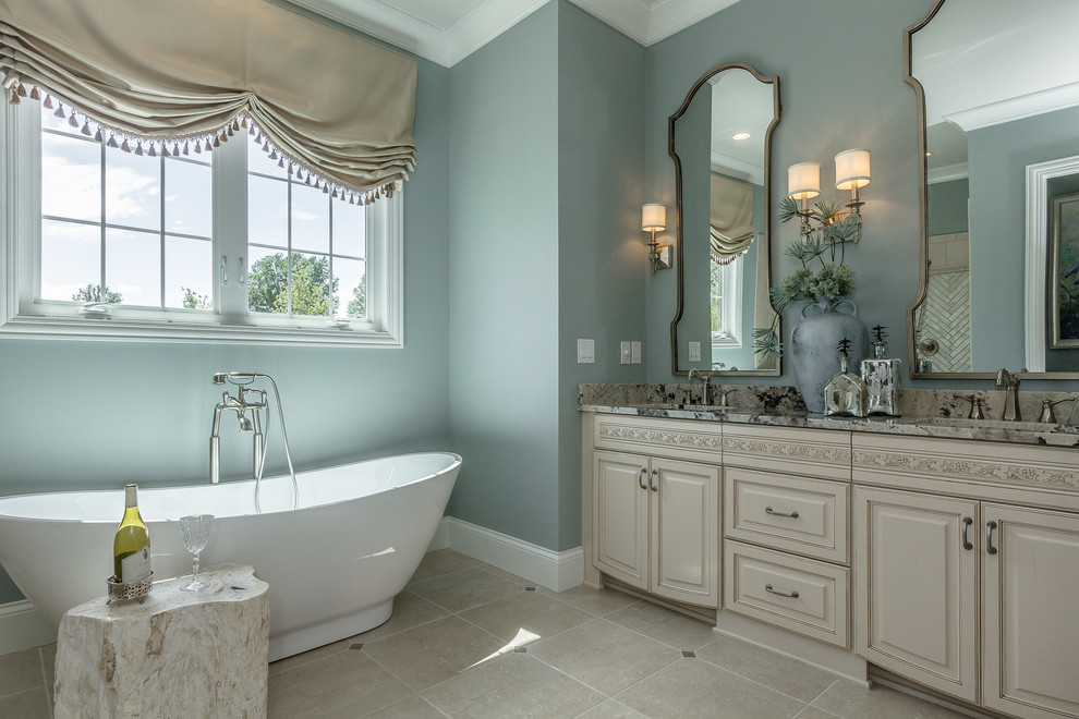 Diseño de cuarto de baño tradicional con lavabo bajoencimera, armarios con paneles con relieve, puertas de armario beige, paredes azules y bañera exenta