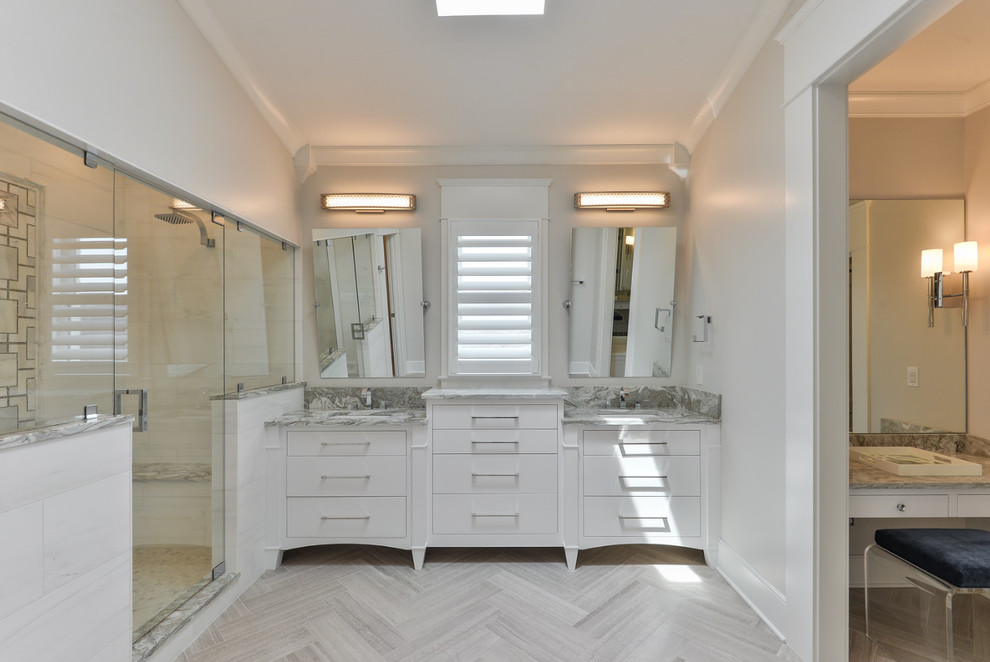 Réalisation d'une salle de bain principale tradition de taille moyenne avec un placard à porte plane, des portes de placard blanches, une baignoire indépendante, une douche d'angle, un carrelage gris, un carrelage blanc, des dalles de pierre, un mur blanc, un sol en vinyl, un lavabo encastré et un plan de toilette en marbre.
