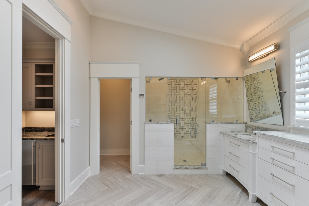 Exemple d'une salle de bain principale chic de taille moyenne avec un placard à porte plane, des portes de placard blanches, une baignoire indépendante, une douche d'angle, un carrelage gris, un carrelage blanc, des dalles de pierre, un mur blanc, un sol en vinyl, un lavabo encastré et un plan de toilette en marbre.