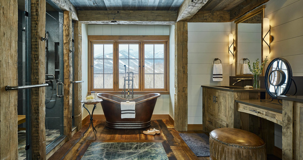 Rustic bathroom in Burlington with shaker cabinets, medium wood cabinets, a freestanding bath, an alcove shower, black tiles, white walls, medium hardwood flooring, a submerged sink, brown floors, a hinged door and black worktops.