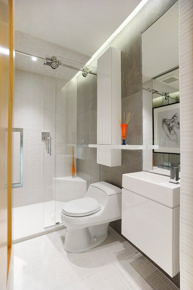 This is an example of a contemporary bathroom in Vancouver with a console sink, flat-panel cabinets, white cabinets, an alcove shower, white walls, porcelain flooring, a one-piece toilet and grey tiles.