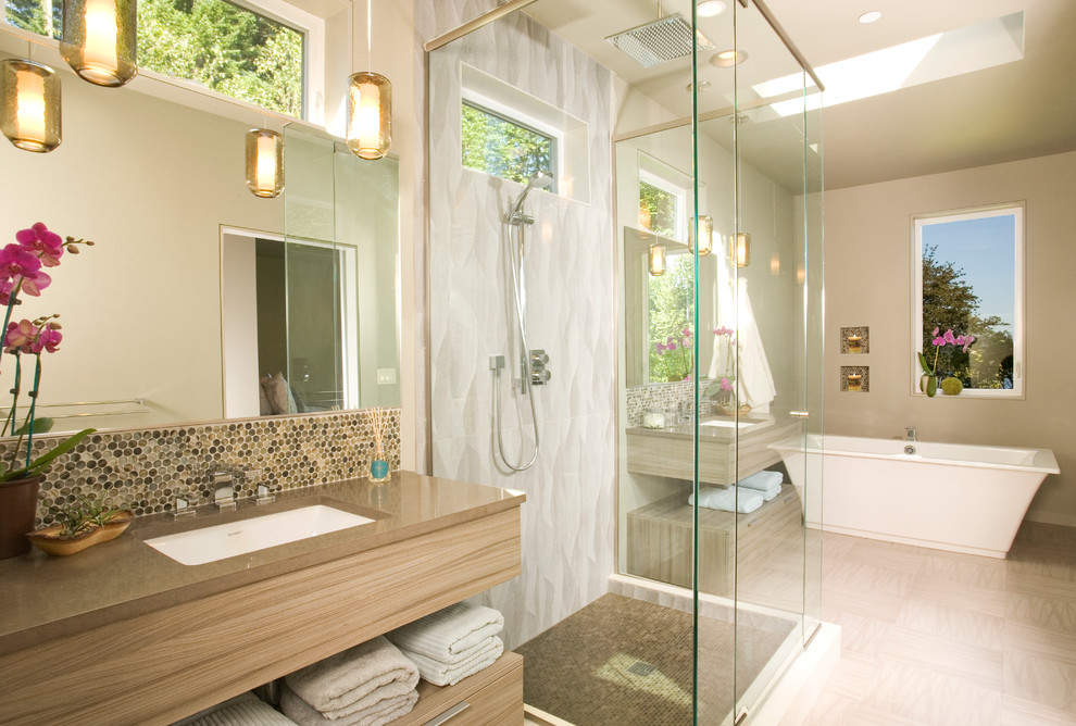 Inredning av ett modernt stort en-suite badrum, med ett undermonterad handfat, skåp i ljust trä, ett fristående badkar, beige väggar, släta luckor, en dusch i en alkov, beige kakel, mosaik, vinylgolv och bänkskiva i akrylsten