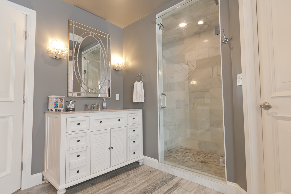 Cette photo montre une grande douche en alcôve principale chic avec des portes de placard blanches, une baignoire indépendante, un carrelage beige, un mur gris, un sol en vinyl, un lavabo encastré et des carreaux de porcelaine.