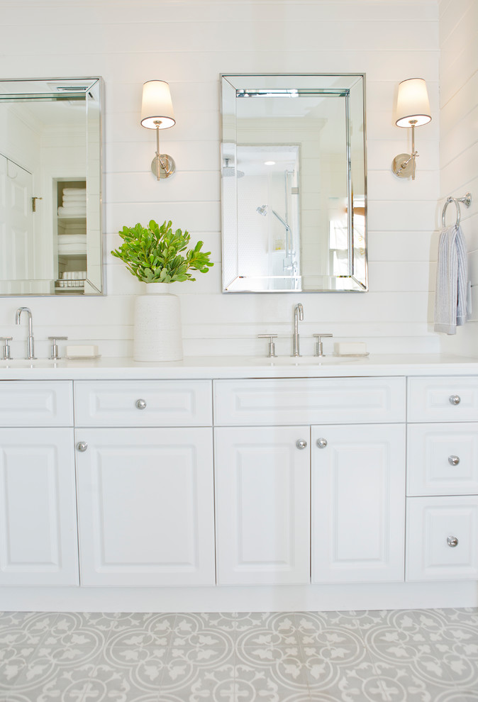 Пример оригинального дизайна: маленькая главная ванная комната в морском стиле с фасадами с выступающей филенкой, белыми фасадами, накладной ванной, душем над ванной, унитазом-моноблоком, белой плиткой, мраморной плиткой, белыми стенами, полом из цементной плитки, врезной раковиной, мраморной столешницей, серым полом и душем с распашными дверями для на участке и в саду