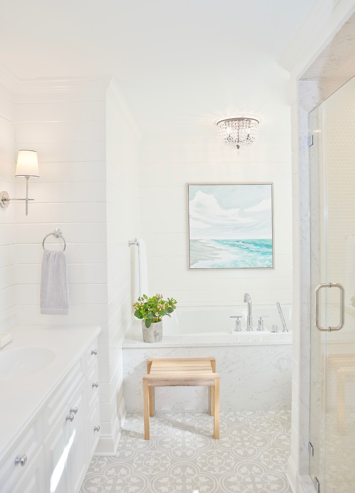 Inspiration for a small coastal master white tile and marble tile cement tile floor and gray floor bathroom remodel in New York with raised-panel cabinets, white cabinets, a one-piece toilet, white walls, an undermount sink, marble countertops and a hinged shower door