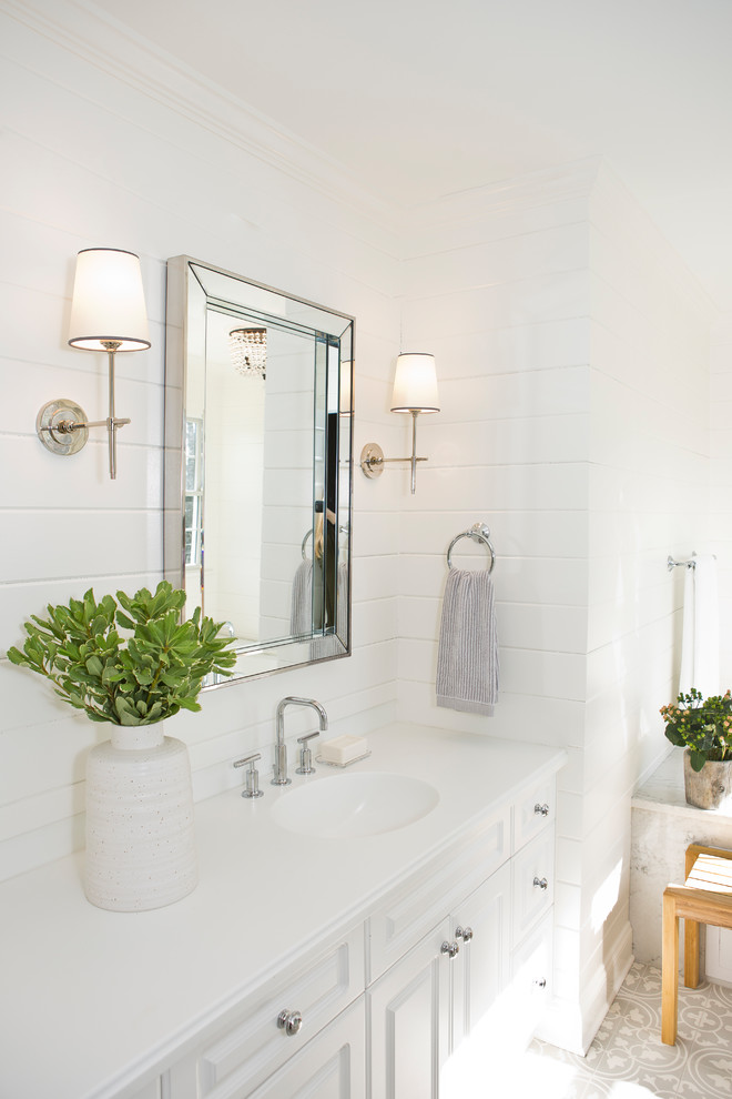 Example of a small beach style master white tile and marble tile cement tile floor and gray floor bathroom design in New York with raised-panel cabinets, white cabinets, a one-piece toilet, white walls, an undermount sink, marble countertops and a hinged shower door