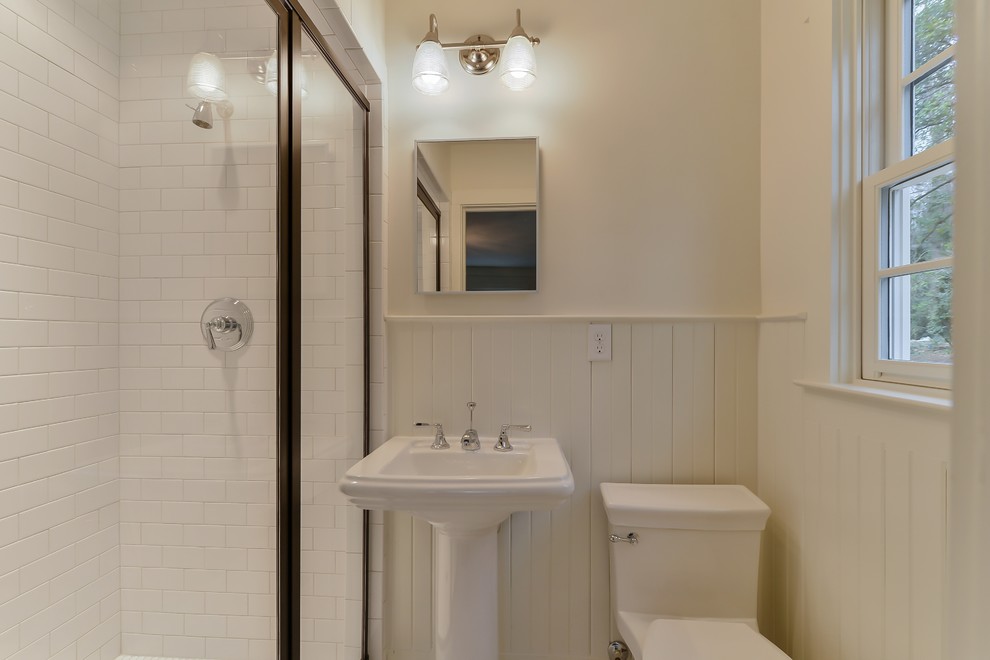 Inredning av ett klassiskt mellanstort badrum för barn, med en dusch i en alkov, en toalettstol med hel cisternkåpa, vita väggar och ett piedestal handfat