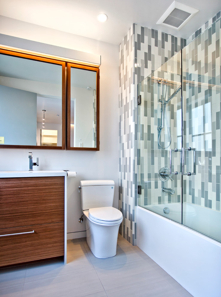 Example of a mid-sized trendy 3/4 blue tile, gray tile, white tile and ceramic tile porcelain tile bathroom design in Sacramento with flat-panel cabinets, dark wood cabinets, an undermount sink, solid surface countertops, a one-piece toilet and white walls