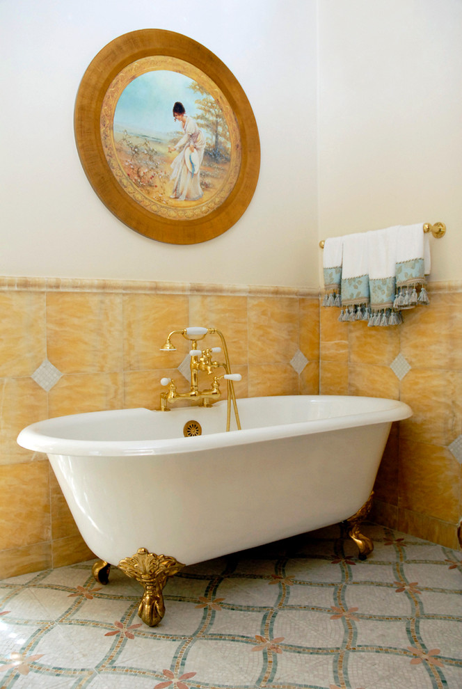 На фото: главная ванная комната среднего размера в классическом стиле с ванной на ножках, бежевой плиткой, каменной плиткой, полом из мозаичной плитки, раздельным унитазом, белыми стенами, накладной раковиной, мраморной столешницей и бежевым полом с