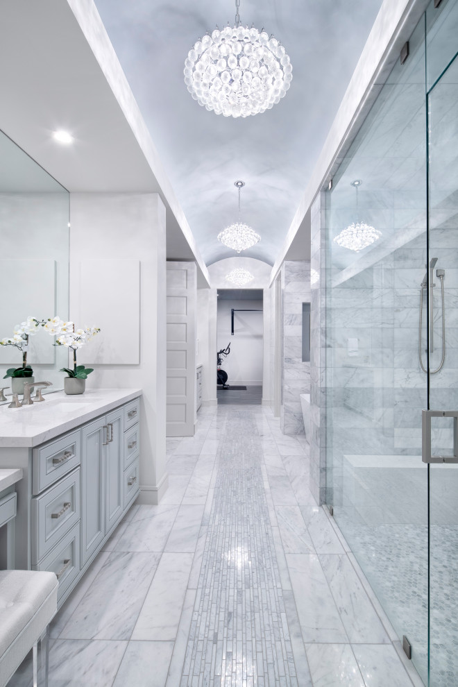 Источник вдохновения для домашнего уюта: большая главная ванная комната в стиле кантри с фасадами с утопленной филенкой, синими фасадами, отдельно стоящей ванной, душем в нише, унитазом-моноблоком, серой плиткой, плиткой мозаикой, белыми стенами, полом из мозаичной плитки, врезной раковиной, серым полом, душем с распашными дверями, белой столешницей, сиденьем для душа, тумбой под две раковины, встроенной тумбой, сводчатым потолком и столешницей из искусственного кварца