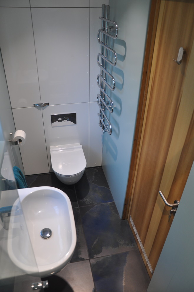 Пример оригинального дизайна: маленькая главная ванная комната в стиле модернизм с плоскими фасадами, белыми фасадами, душевой комнатой, инсталляцией, зеленой плиткой, зелеными стенами, полом из керамогранита, подвесной раковиной, столешницей из ламината, синим полом, душем с распашными дверями и зеленой столешницей для на участке и в саду