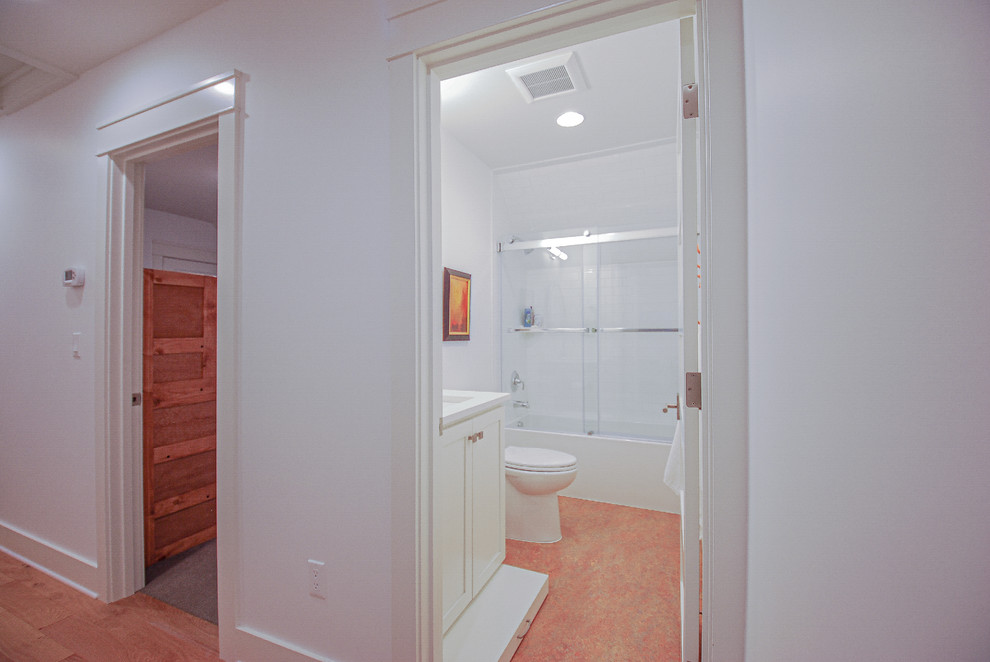 Inspiration for a large victorian family bathroom in Portland with shaker cabinets, white cabinets, an alcove bath, a shower/bath combination, a two-piece toilet, white tiles, metro tiles, white walls, lino flooring, a submerged sink, quartz worktops, orange floors, a sliding door and white worktops.