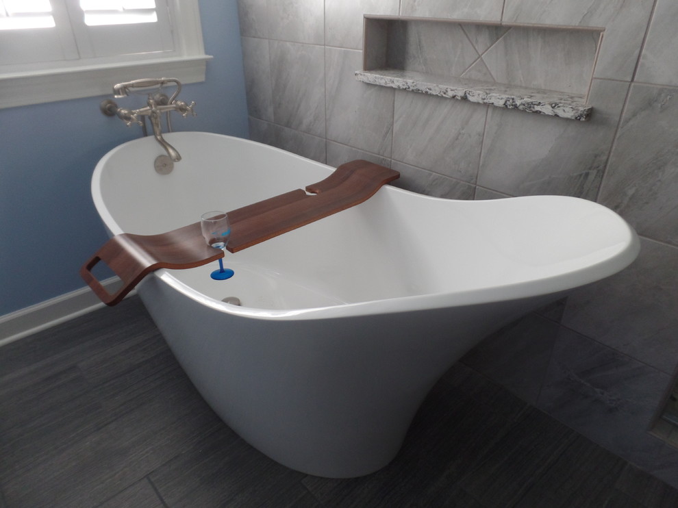 This is an example of a large classic ensuite bathroom in Other with freestanding cabinets, dark wood cabinets, a freestanding bath, a double shower, a one-piece toilet, grey tiles, porcelain tiles, blue walls, porcelain flooring, a submerged sink, engineered stone worktops, black floors and a hinged door.