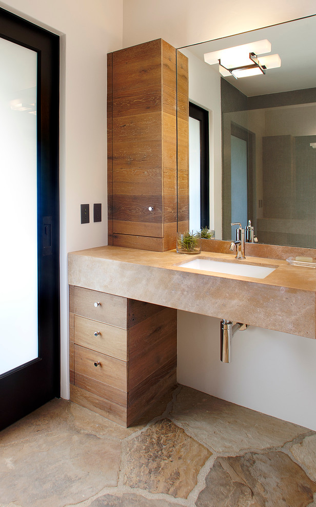 Réalisation d'une salle de bain design en bois brun avec un placard à porte plane, un mur blanc et un lavabo encastré.