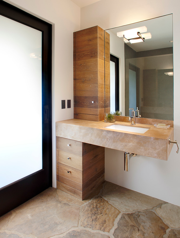 Ejemplo de cuarto de baño mediterráneo con lavabo bajoencimera, armarios con paneles lisos, puertas de armario de madera en tonos medios y paredes blancas