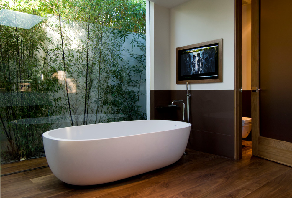 Inredning av ett modernt stort en-suite badrum, med ett fristående badkar, mellanmörkt trägolv och brunt golv