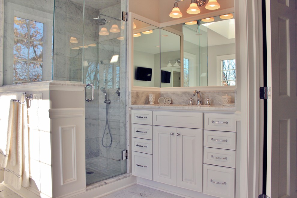Foto på ett stort vintage en-suite badrum, med luckor med infälld panel, vita skåp, ett fristående badkar, en hörndusch, en toalettstol med separat cisternkåpa, vit kakel, grå väggar, marmorgolv, ett undermonterad handfat och marmorbänkskiva