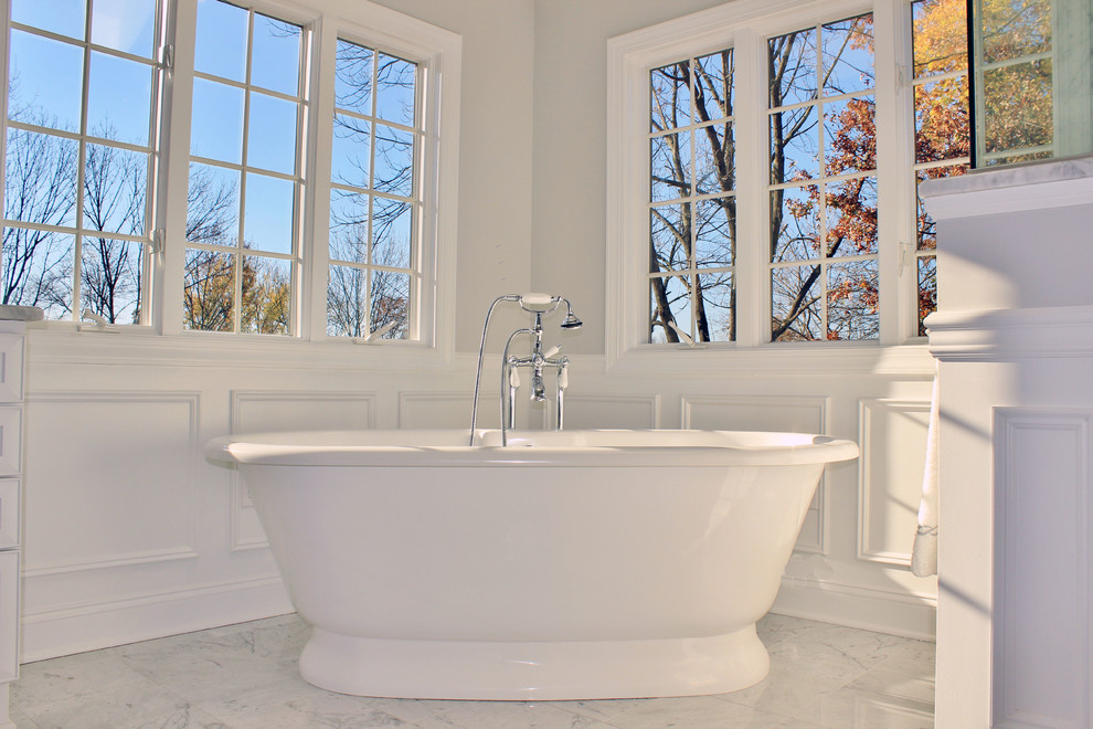 Inspiration for a large traditional ensuite bathroom in Philadelphia with recessed-panel cabinets, white cabinets, a freestanding bath, a corner shower, a two-piece toilet, white tiles, grey walls, marble flooring, a submerged sink and marble worktops.