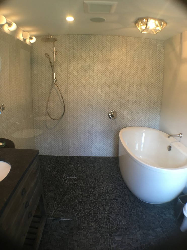 Idéer för ett mellanstort klassiskt en-suite badrum, med släta luckor, skåp i mellenmörkt trä, ett fristående badkar, en kantlös dusch, vit kakel, porslinskakel, beige väggar, klinkergolv i småsten, bänkskiva i akrylsten och grått golv