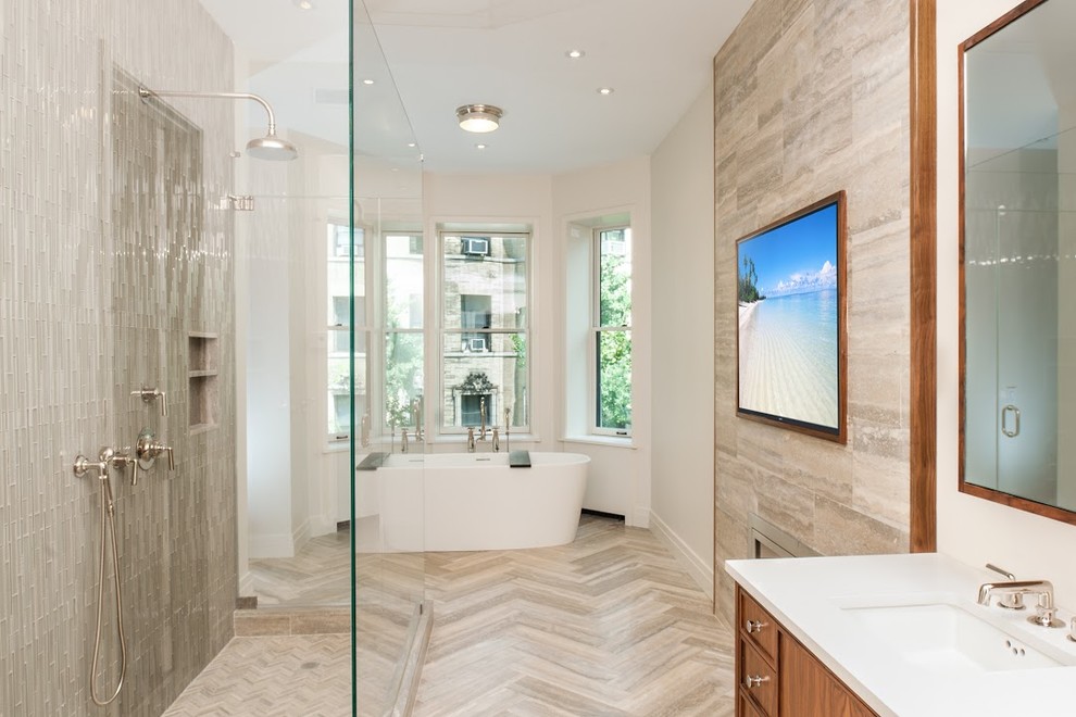 Large contemporary ensuite bathroom in New York with recessed-panel cabinets, medium wood cabinets, a freestanding bath, an alcove shower, beige tiles, porcelain tiles, white walls, porcelain flooring, a submerged sink, engineered stone worktops, brown floors and an open shower.
