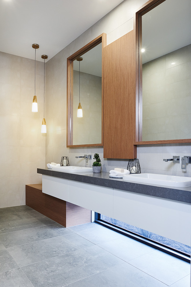 Large contemporary ensuite bathroom in Melbourne with freestanding cabinets, white cabinets, a freestanding bath, an alcove shower, a one-piece toilet, grey tiles, ceramic tiles, beige walls, ceramic flooring, a built-in sink and wooden worktops.