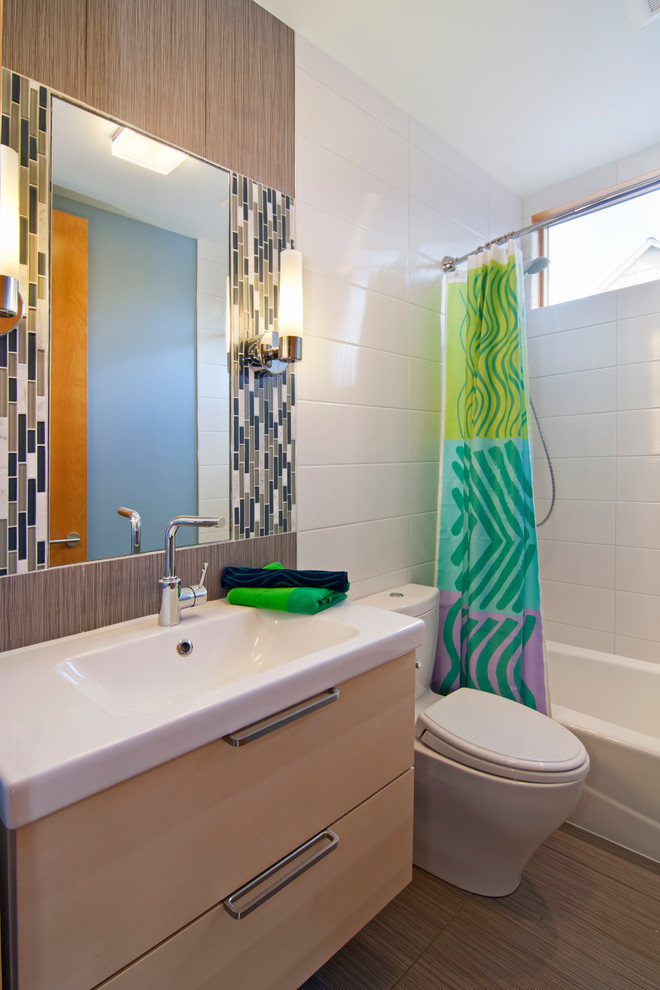 Стильный дизайн: ванная комната в современном стиле с монолитной раковиной, плоскими фасадами, светлыми деревянными фасадами, ванной в нише, душем над ванной, белой плиткой, удлиненной плиткой и шторкой для ванной - последний тренд