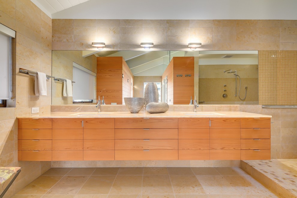 オースティンにある広いミッドセンチュリースタイルのおしゃれなマスターバスルーム (フラットパネル扉のキャビネット、淡色木目調キャビネット、洗い場付きシャワー、ベージュのタイル、アンダーカウンター洗面器、オニキスの洗面台、オープンシャワー) の写真