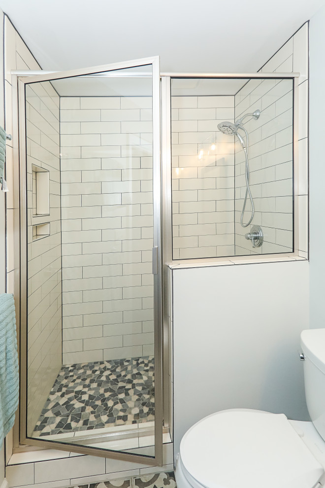 На фото: ванная комната среднего размера в стиле неоклассика (современная классика) с фасадами с утопленной филенкой, синими фасадами, ванной в нише, душем в нише, раздельным унитазом, белой плиткой, керамогранитной плиткой, серыми стенами, полом из керамогранита, душевой кабиной, врезной раковиной, столешницей из искусственного кварца, разноцветным полом, душем с распашными дверями и белой столешницей