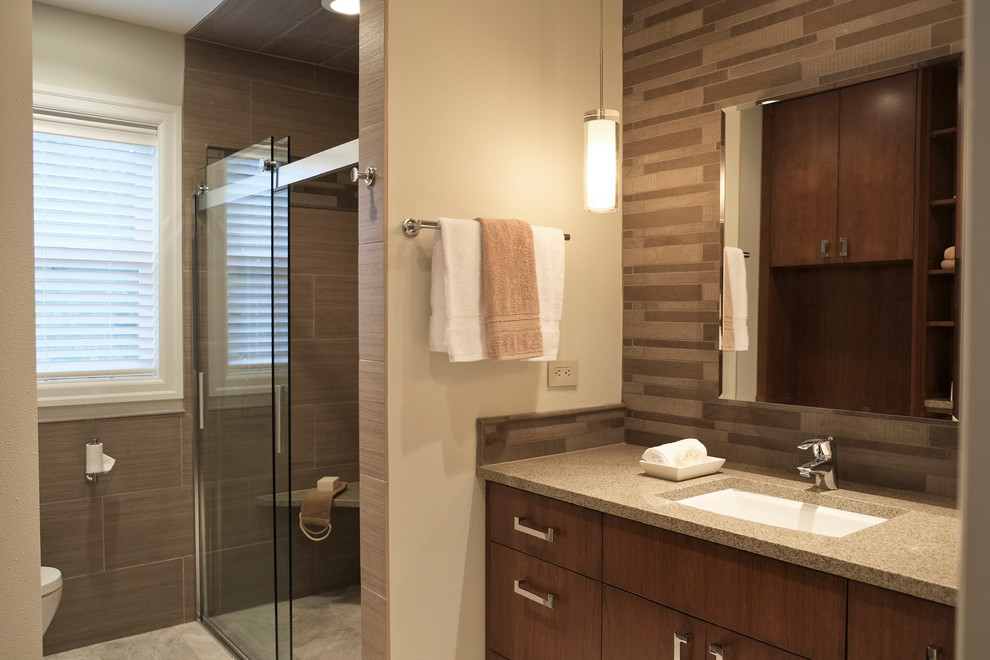 Example of a mid-sized trendy master brown tile and porcelain tile porcelain tile doorless shower design in Seattle with an undermount sink, flat-panel cabinets, medium tone wood cabinets, quartz countertops and a one-piece toilet