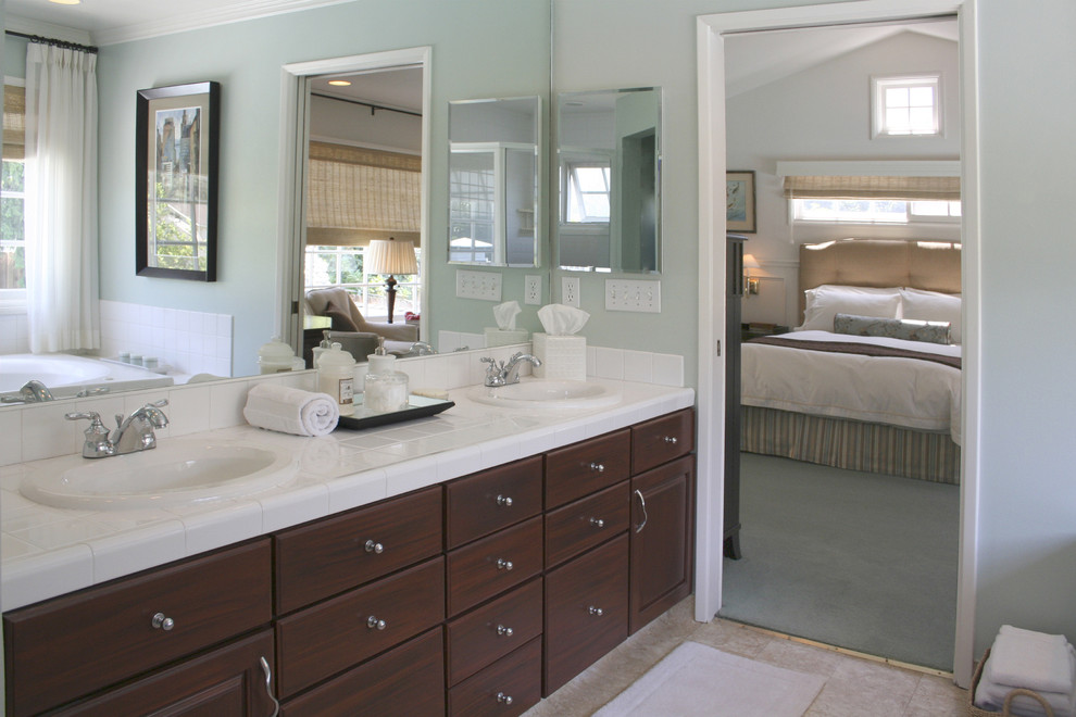Foto di una stanza da bagno padronale classica con lavabo da incasso, ante con bugna sagomata, ante in legno bruno, top piastrellato, piastrelle bianche, piastrelle in gres porcellanato, pareti blu e top bianco