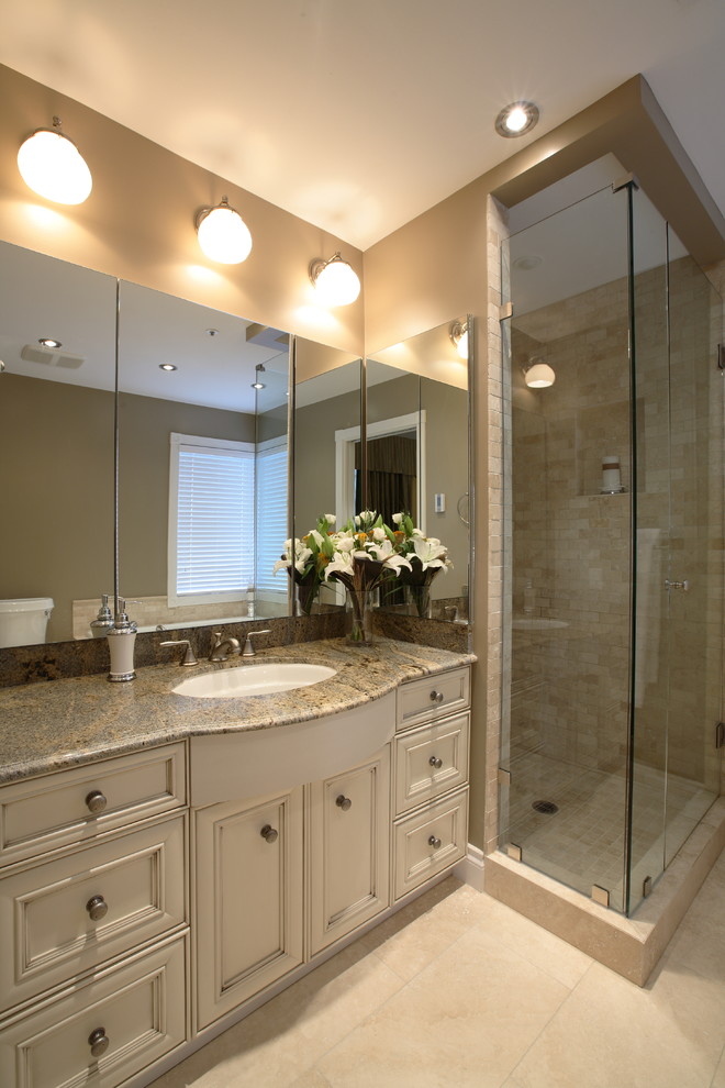 Medium sized classic ensuite bathroom in Vancouver with a submerged sink, recessed-panel cabinets, white cabinets, granite worktops, a built-in bath, a corner shower, a two-piece toilet, beige tiles, stone tiles, brown walls and travertine flooring.