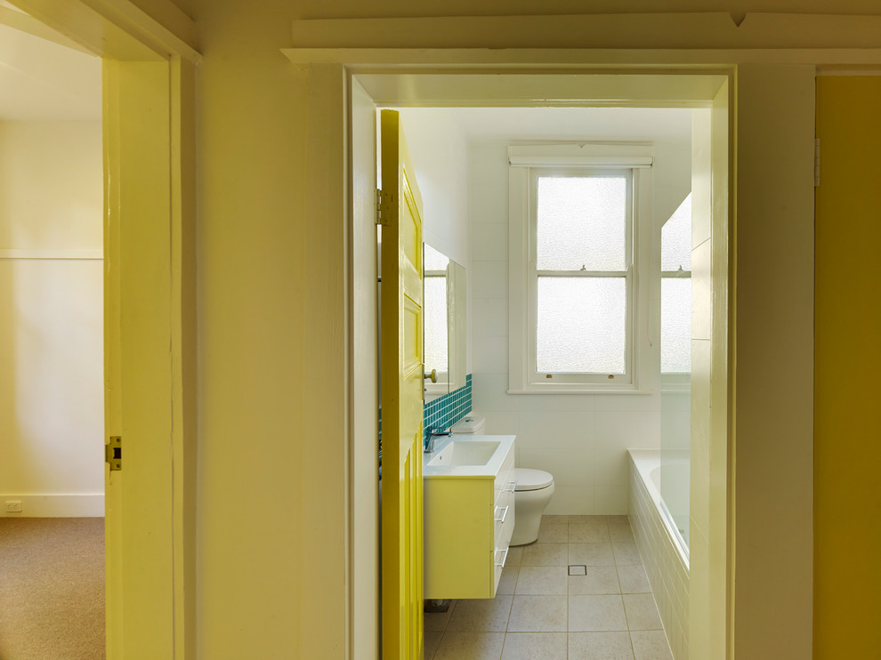Inspiration pour une salle de bain minimaliste de taille moyenne avec un plan vasque, des portes de placard blanches, un plan de toilette en surface solide, une baignoire posée, un combiné douche/baignoire, WC à poser, un carrelage bleu, un mur blanc et un sol en carrelage de céramique.