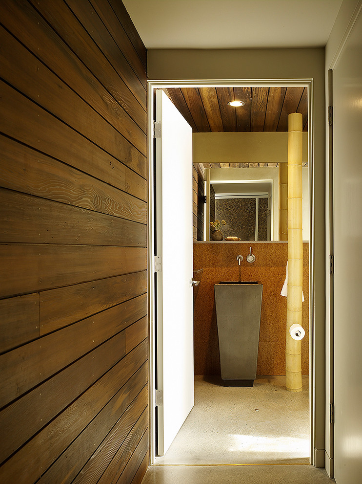Foto på ett mellanstort funkis badrum, med ett piedestal handfat, glaskakel, orange väggar och betonggolv