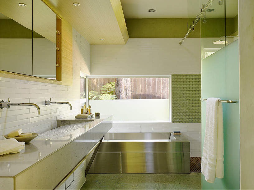 На фото: большая ванная комната в современном стиле с раковиной с несколькими смесителями, столешницей из бетона, отдельно стоящей ванной, открытым душем, белой плиткой, белыми стенами и бетонным полом