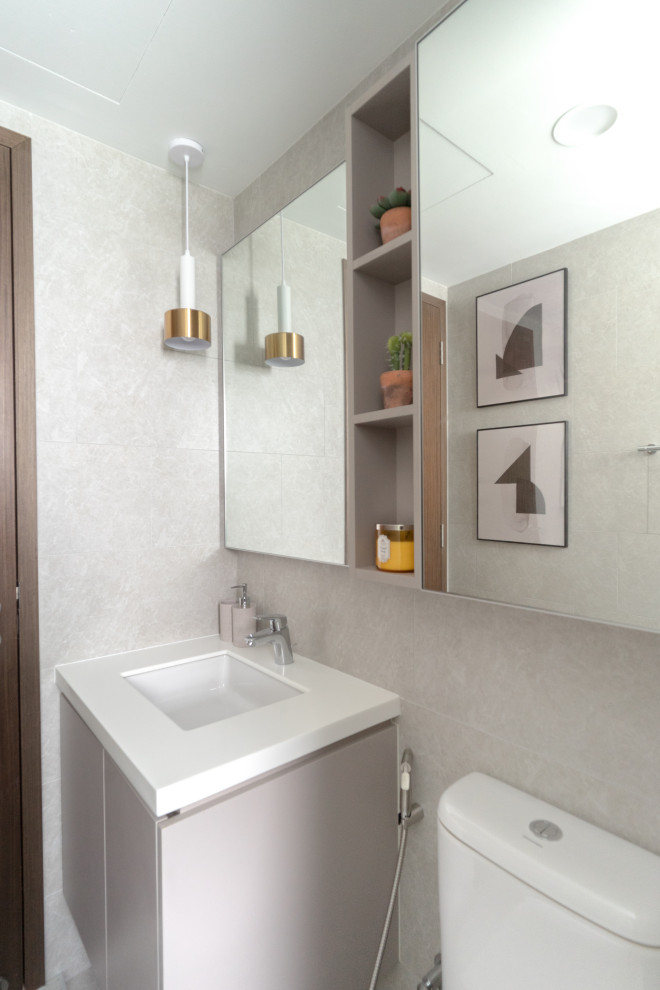 Modernes Badezimmer mit flächenbündigen Schrankfronten, grauen Schränken, grauen Fliesen, Unterbauwaschbecken und weißer Waschtischplatte in Singapur