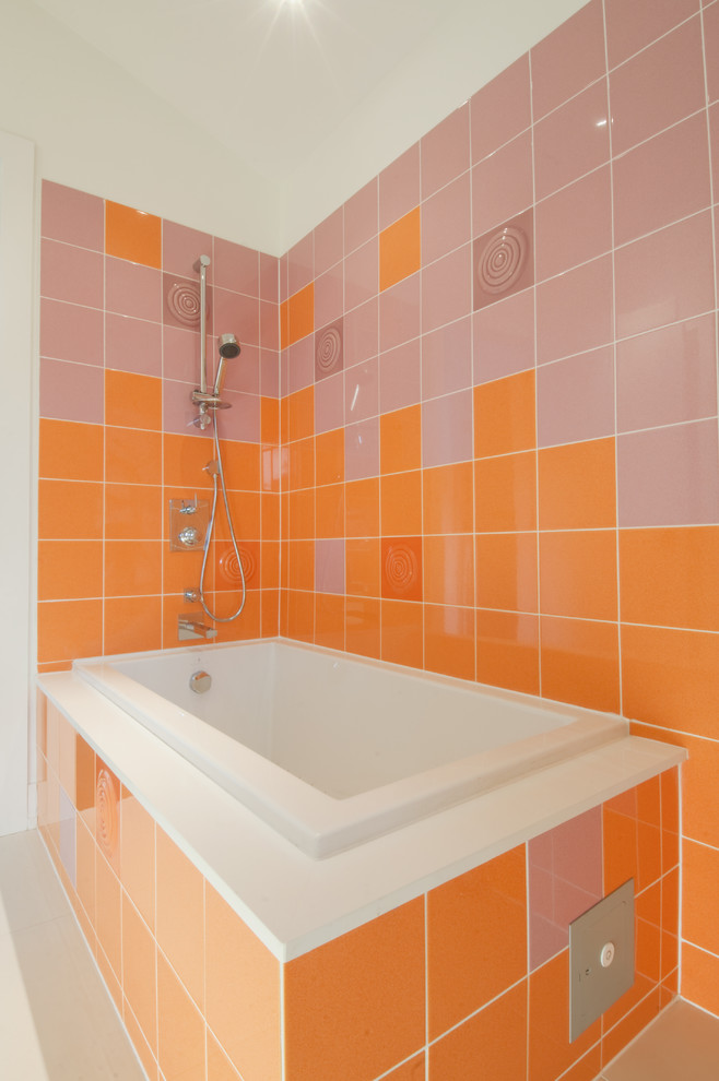 Стильный дизайн: ванная комната в современном стиле с душем над ванной, оранжевой плиткой и накладной ванной - последний тренд