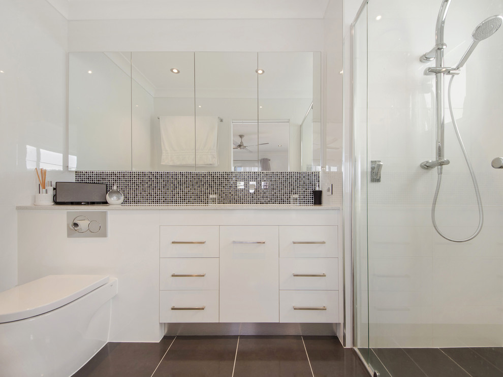 Exempel på ett mellanstort modernt badrum med dusch, med ett undermonterad handfat, släta luckor, vita skåp, en dusch i en alkov, en toalettstol med hel cisternkåpa, vit kakel och vita väggar
