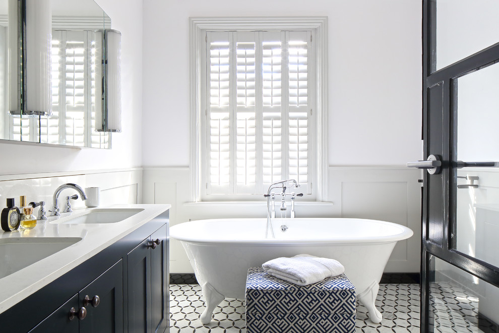 Modelo de cuarto de baño principal clásico renovado con armarios estilo shaker, puertas de armario azules, bañera con patas, paredes blancas y lavabo bajoencimera