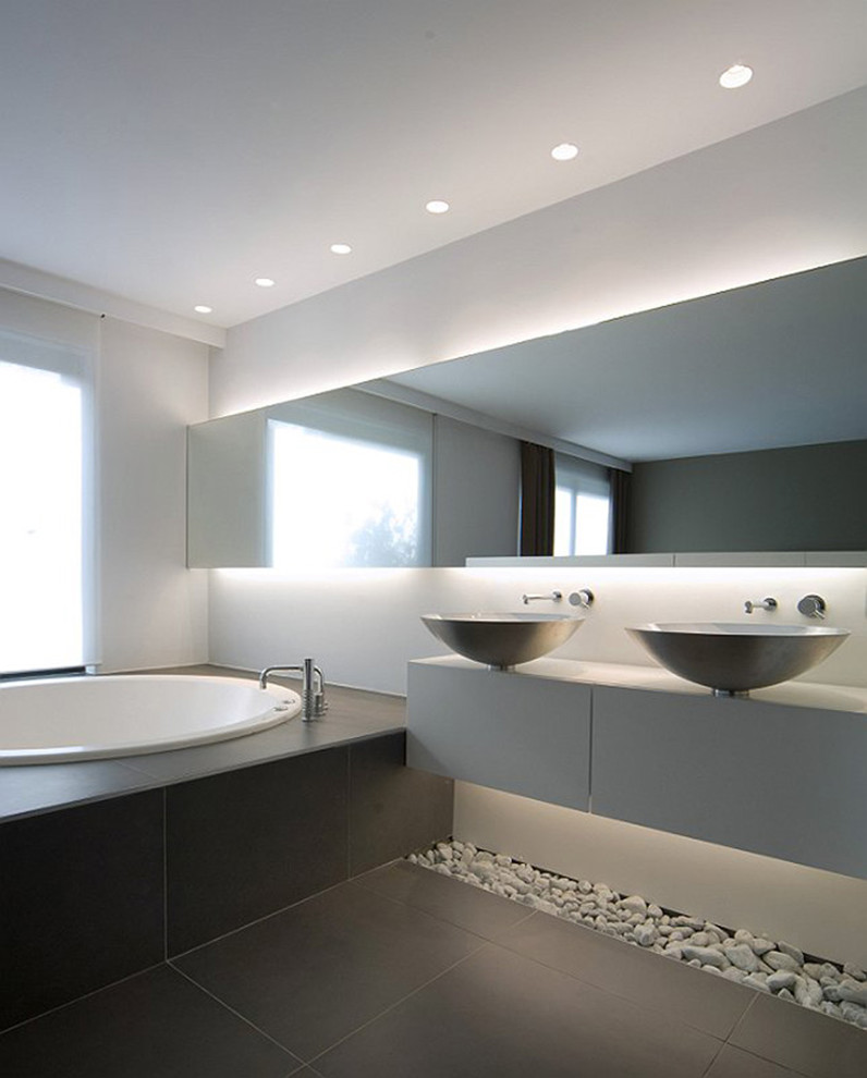Imagen de cuarto de baño principal, contemporáneo, grande, con armarios con paneles lisos, puertas de armario blancas, suelo de baldosas de cerámica, paredes grises, lavabo sobreencimera, baldosas y/o azulejos grises y bañera encastrada