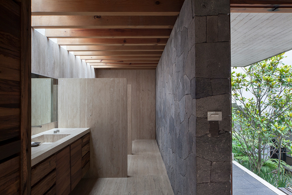 Cette photo montre une salle de bain moderne en bois foncé avec un lavabo intégré et un mur en pierre.