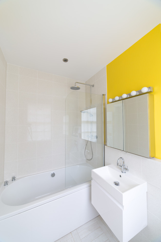 他の地域にある小さなコンテンポラリースタイルのおしゃれなマスターバスルーム (家具調キャビネット、白いキャビネット、ドロップイン型浴槽、シャワー付き浴槽	、壁掛け式トイレ、マルチカラーのタイル、黄色い壁、オーバーカウンターシンク) の写真