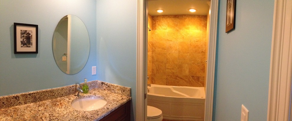 Exemple d'une salle de bain chic en bois foncé de taille moyenne pour enfant avec un lavabo encastré, un placard avec porte à panneau encastré, un plan de toilette en granite, une baignoire en alcôve, WC séparés, un carrelage multicolore, un carrelage de pierre, un mur bleu et un sol en travertin.