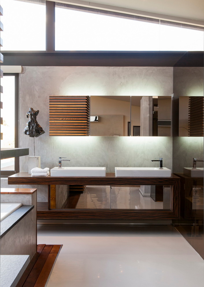 Foto de cuarto de baño actual con lavabo sobreencimera, armarios con paneles lisos, bañera encastrada y paredes grises