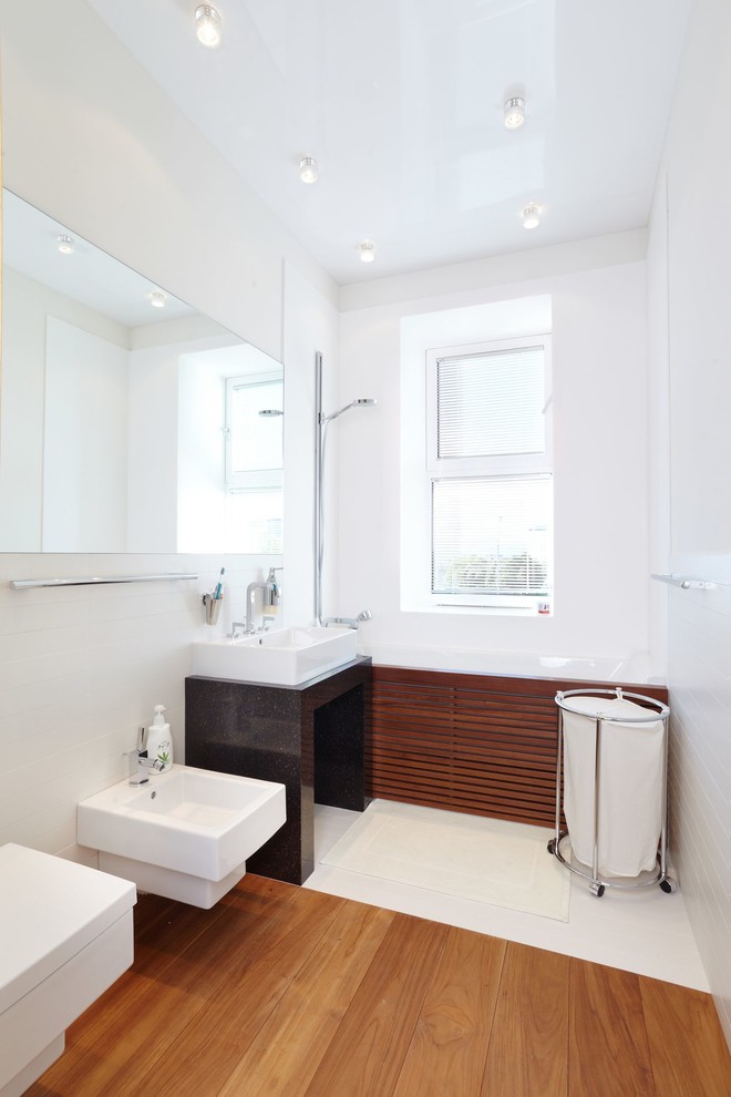 Источник вдохновения для домашнего уюта: главная ванная комната в современном стиле с раковиной с пьедесталом, ванной в нише, душем над ванной, биде, белыми стенами и паркетным полом среднего тона