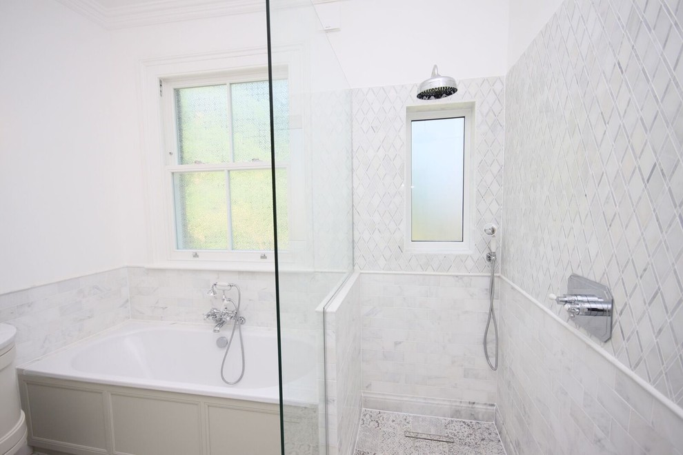 Inspiration for a large victorian ensuite wet room bathroom in Other with shaker cabinets, beige cabinets, a corner bath, a wall mounted toilet, grey tiles, porcelain tiles, white walls, porcelain flooring, a built-in sink, marble worktops, grey floors, an open shower and white worktops.