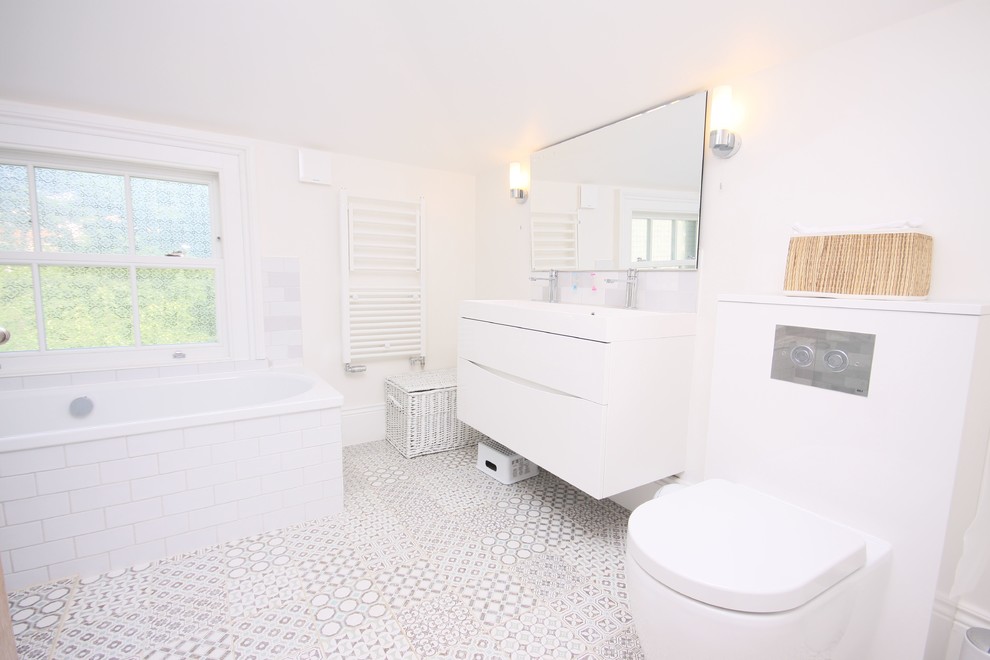 Bild på ett mellanstort vintage vit vitt badrum, med vita skåp, ett hörnbadkar, våtrum, en vägghängd toalettstol, grå kakel, porslinskakel, vita väggar, marmorbänkskiva, grått golv och med dusch som är öppen